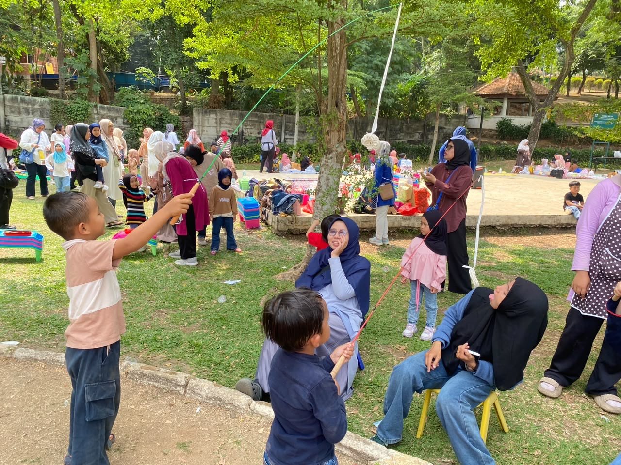 Anak-anak dan orang dewasa mengikuti permainan bersama di luar ruangan